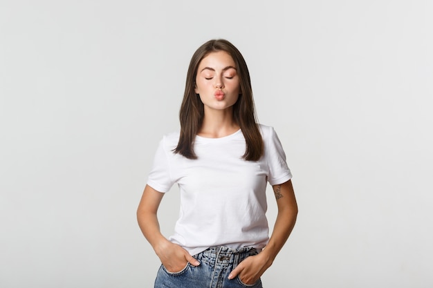 Jolie fille stupide ferme les yeux et fait la moue, en attente de baiser