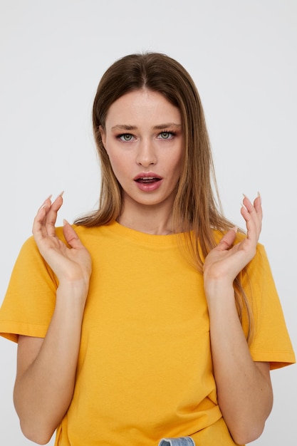 Jolie fille en t-shirt jaune posant des gestes de la main sur fond clair