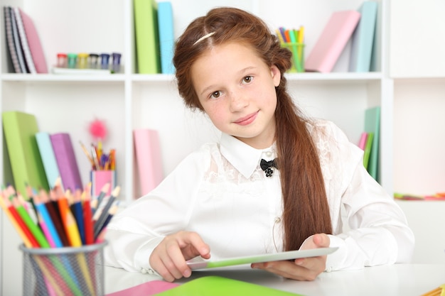 Jolie fille avec tablette sur le lieu de travail en classe