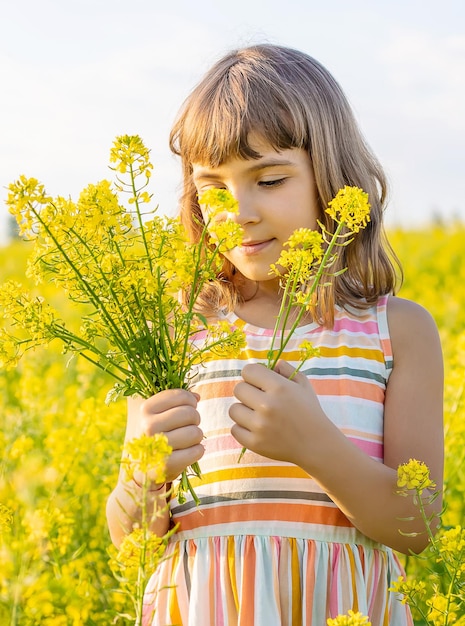 Une jolie fille tenant des fleurs alors qu'elle se tient dans le champ