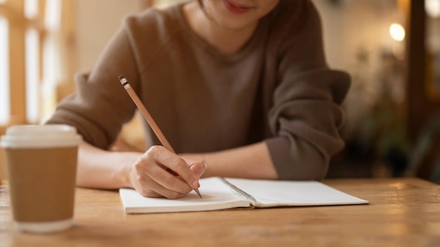 Une jolie fille tenant son journal ou écrivant quelque chose dans son carnet dans un café