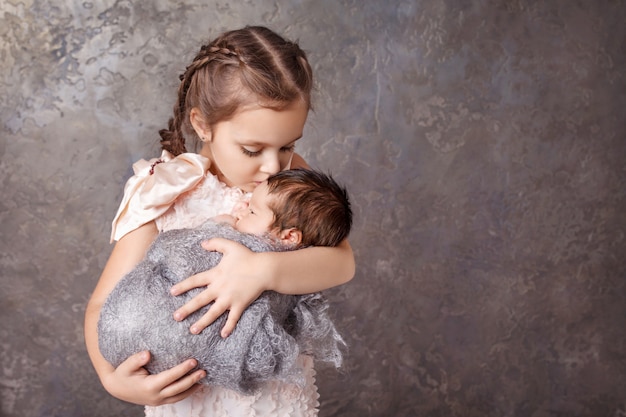 Jolie fille tenant son petit frère. Soeur heureuse embrassant son petit frère nouveau-né. fond