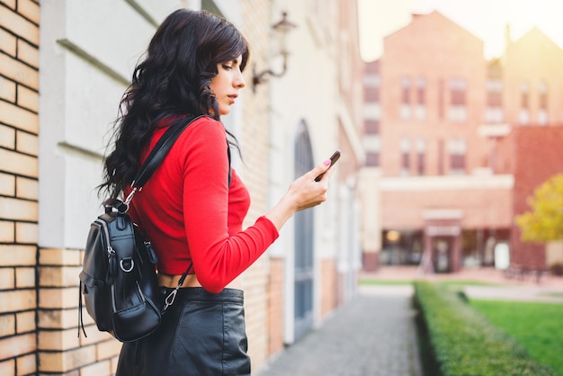 Jolie Fille De Touriste Aux Cheveux Noirs Marchant Dans La Rue De La Vieille Ville Avec Un Téléphone Portable Dans Les Mains, Application De Carte De Navigation