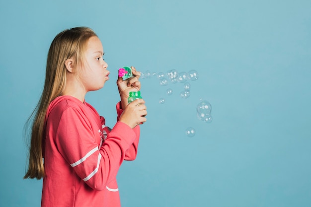 Jolie fille trisomique soufflant des bulles