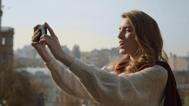 Photo jolie fille utilisant un smartphone dans la rue femme douce prenant une photo de selfie par téléphone