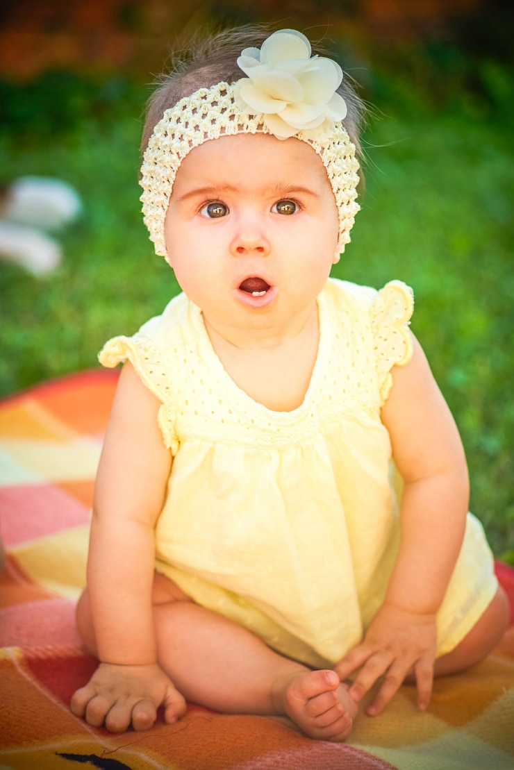 Photo une jolie fille en vêtements de bébé jaunes dans le jardin.