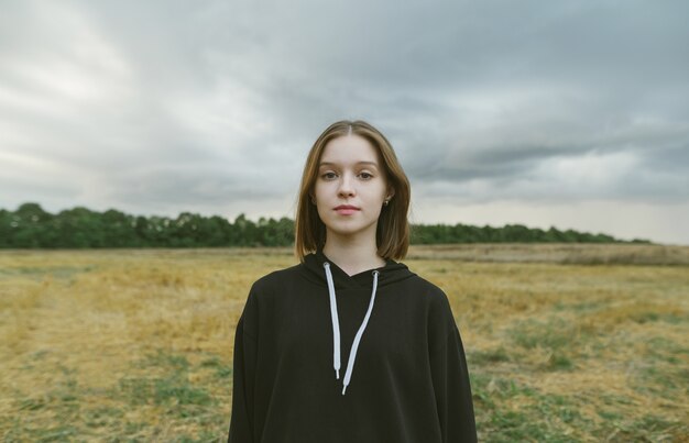 Jolie fille en vêtements décontractés debout dans le champ d'automne