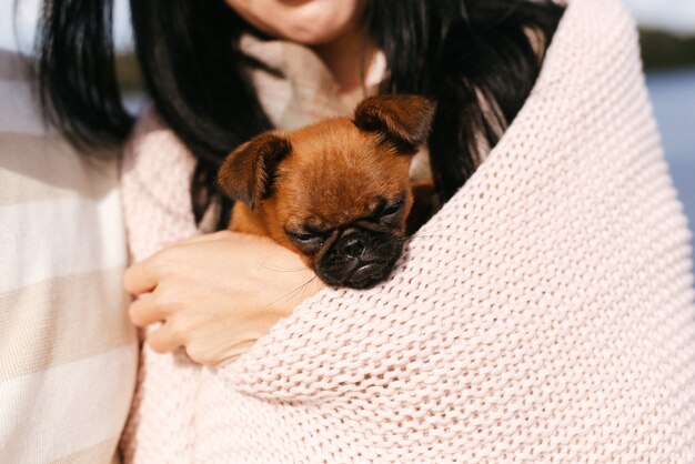 Jolie fille en vêtements légers tient son petit chien dans ses bras