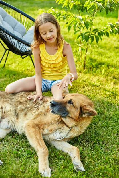 Jolie fille et vieux chien profitent de la journée d'été sur l'herbe dans le parc