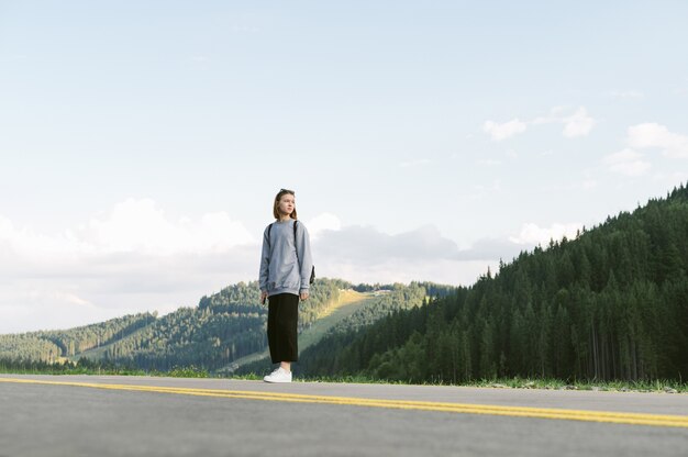 Jolie fille de voyageur regardant de côté près des forêts de conifères de montagne