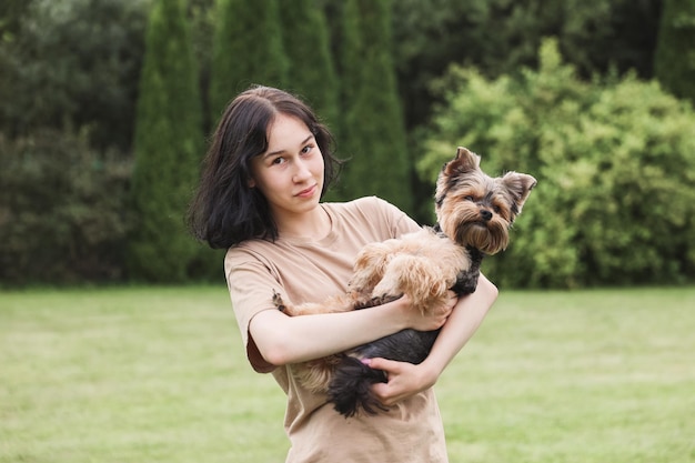 Une jolie fille avec un Yorkshire terrier dans la rue Câlins avec votre petit chien dans le parc