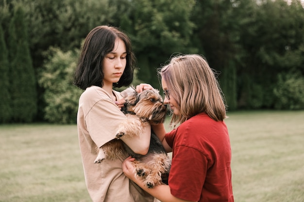 Une jolie fille avec un Yorkshire terrier dans la rue. Câlins avec votre petit chien dans le parc