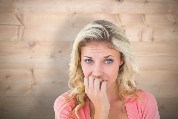 Jolie jeune blonde se sentant nerveuse sur fond de planches de bois blanchies