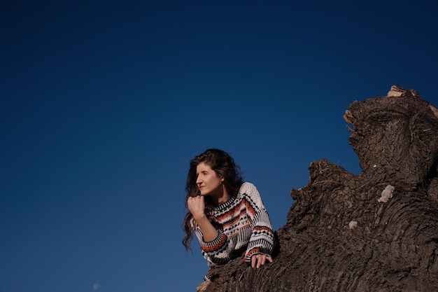 Jolie jeune brune aux cheveux longs contre un ciel bleu ensoleillé.