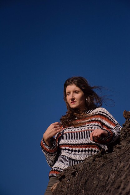 Jolie jeune brune aux cheveux longs contre un ciel bleu ensoleillé.