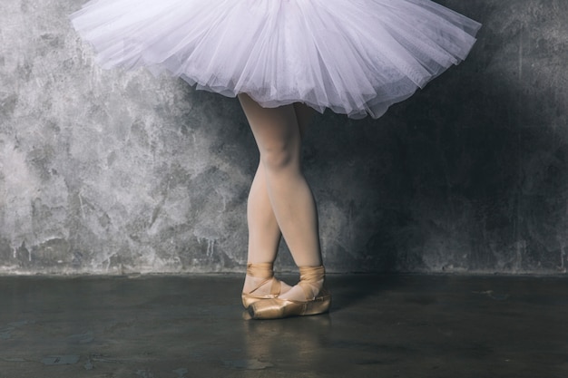 Photo jolie jeune danseuse de ballerine dansant le ballet classique contre un mur rustique