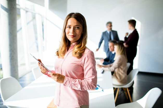 Jolie jeune femme d'affaires à l'aide de tablette numérique au bureau