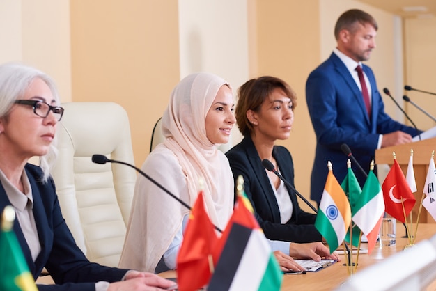 Jolie jeune femme d'affaires musulmane à l'écoute du public après avoir fait rapport et répondu à leurs questions