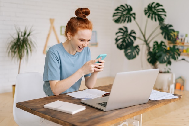 Jolie jeune femme d'affaires rousse joyeuse et heureuse à l'aide d'un téléphone portable