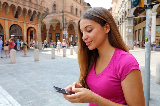 Jolie jeune femme à l'aide de téléphone intelligent sur la rue de la vieille ville. Concept de technologie et de communication.