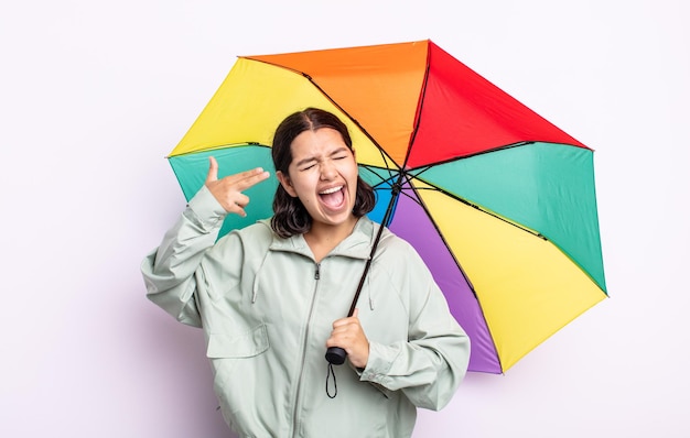 Jolie jeune femme à l'air malheureuse et stressée, geste de suicide faisant signe d'arme à feu. concept de pluie et de parapluie