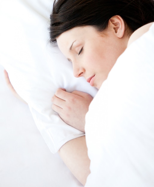 Jolie jeune femme allongée dans un lit en train de dormir