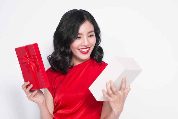 Jolie jeune femme asiatique vêtue d'une robe rouge avec un cadeau
