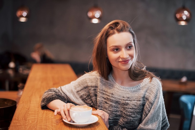 Jolie jeune femme assise au café avec une tasse de thé