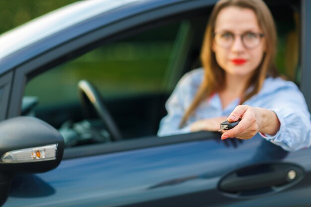 Photo une jolie jeune femme assise dans une voiture avec les clés à la main concept d'achat d'une voiture d'occasion ou une voiture de location