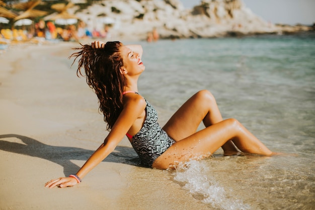 Jolie jeune femme assise sur la plage