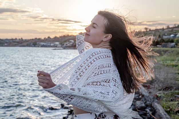 Jolie jeune femme au bord de la mer au coucher du soleil. Belle nature.