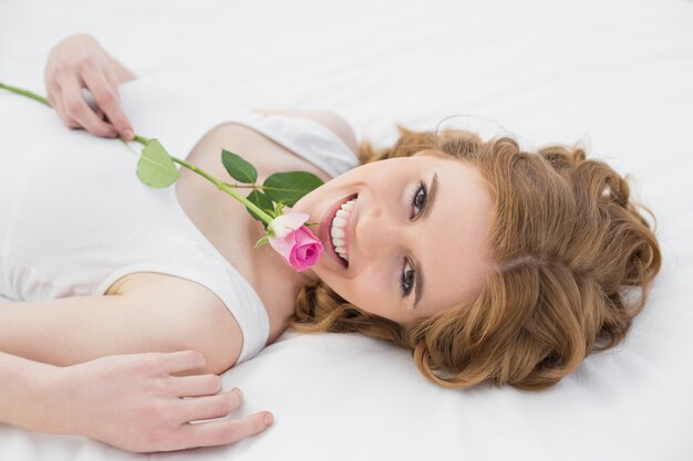 Jolie jeune femme au repos au lit avec rose