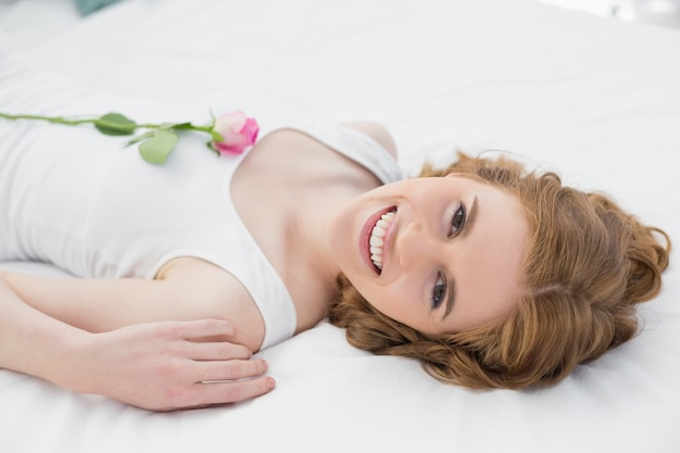 Jolie jeune femme au repos au lit avec une rose