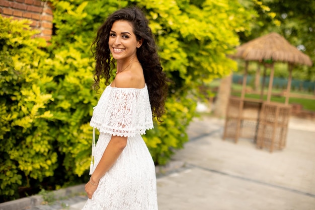 Jolie jeune femme aux cheveux bouclés dans le parc