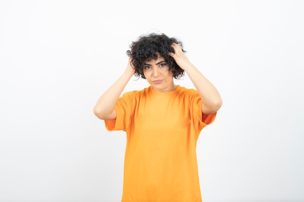 Jolie jeune femme aux cheveux bouclés en t-shirt jaune posant.