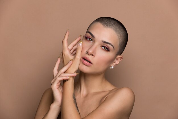 Jolie jeune femme aux cheveux courts posant sur beige