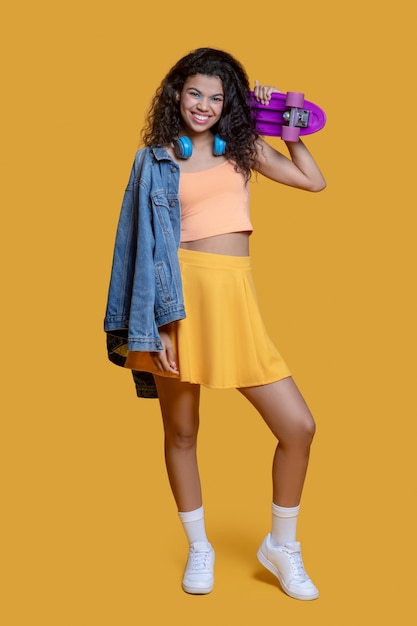 Jolie jeune femme aux cheveux noirs avec une planche à roulettes