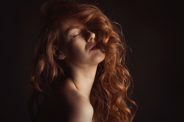 Jolie jeune femme aux yeux fermés dans le noir