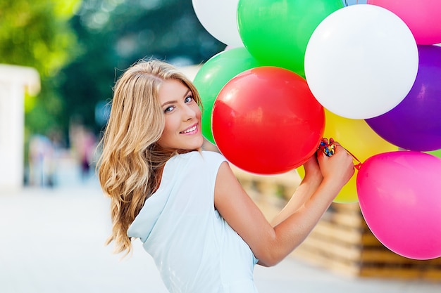 Jolie jeune femme avec des ballons d'anniversaire et boîte-cadeau rouge