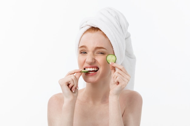 Jolie jeune femme avec une belle peau propre. Masque blanc et concombres