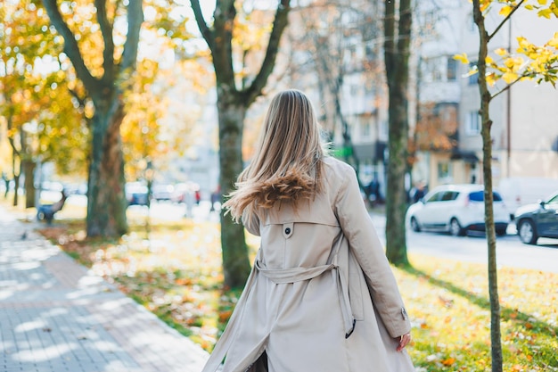 Une jolie jeune femme blonde court dans le parc en automne