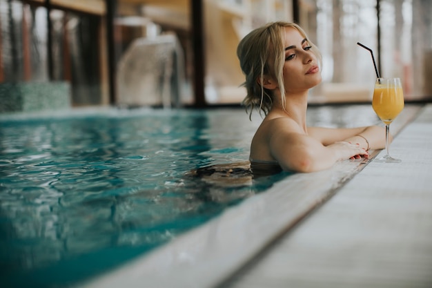 Jolie jeune femme blonde se détendre au bord de la piscine