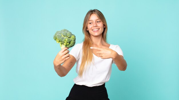 Jolie jeune femme blonde tenant un brocoli