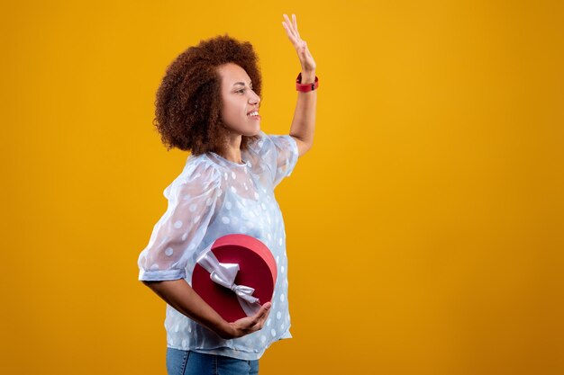 Jolie jeune femme avec une boîte-cadeau rencontrant quelqu'un et agitant les mains