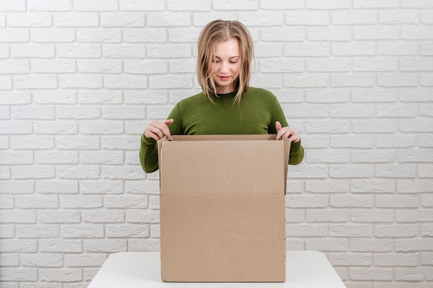 Jolie jeune femme avec une boîte en carton Livrer un colis