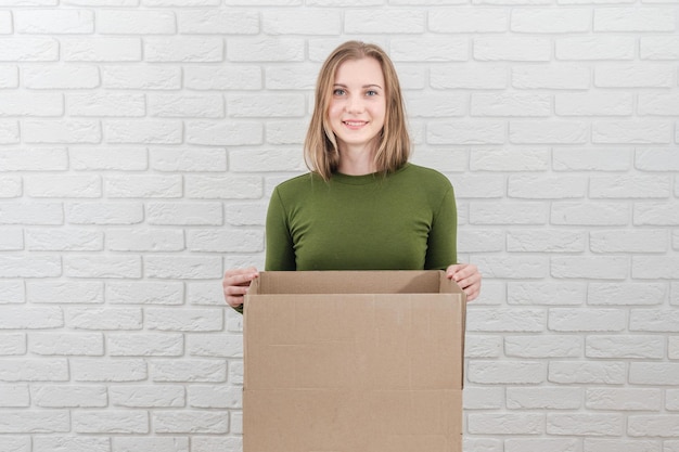 Jolie jeune femme avec une boîte en carton Livrer un colis