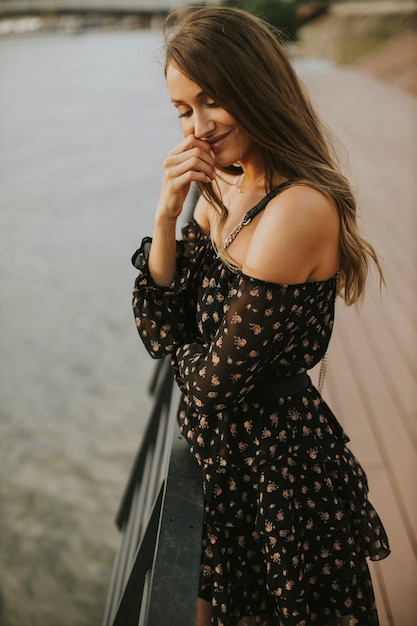 Jolie jeune femme brune aux cheveux longs, debout au bord de la rivière