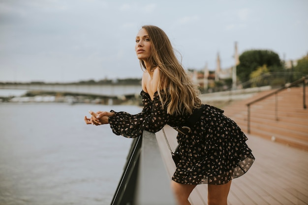 Jolie jeune femme brune aux cheveux longs, debout au bord de la rivière