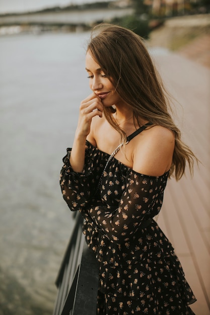 Jolie jeune femme brune aux cheveux longs, debout au bord de la rivière