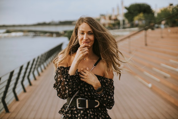 Jolie jeune femme brune aux cheveux longs marchant au bord de la rivière